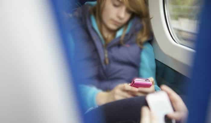 Adolescente en el tren con el móvil