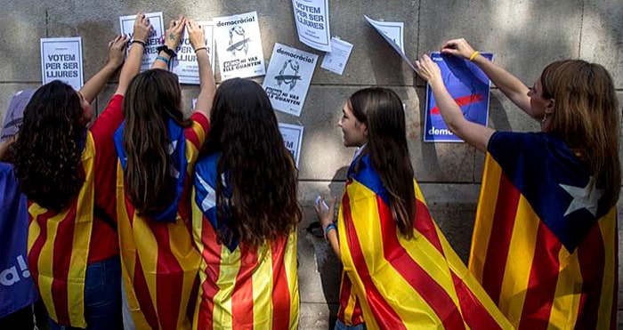 Jóvenes con esteladas y pegando carteles a favor del referéndum ilegal