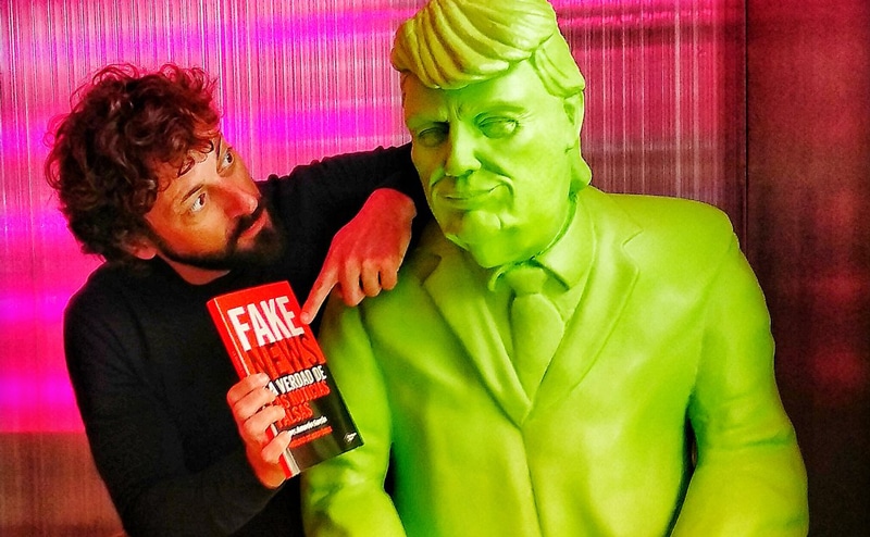 Marc Amorós con el libro 'Fake News' junto a una estatua de Donald Trump
